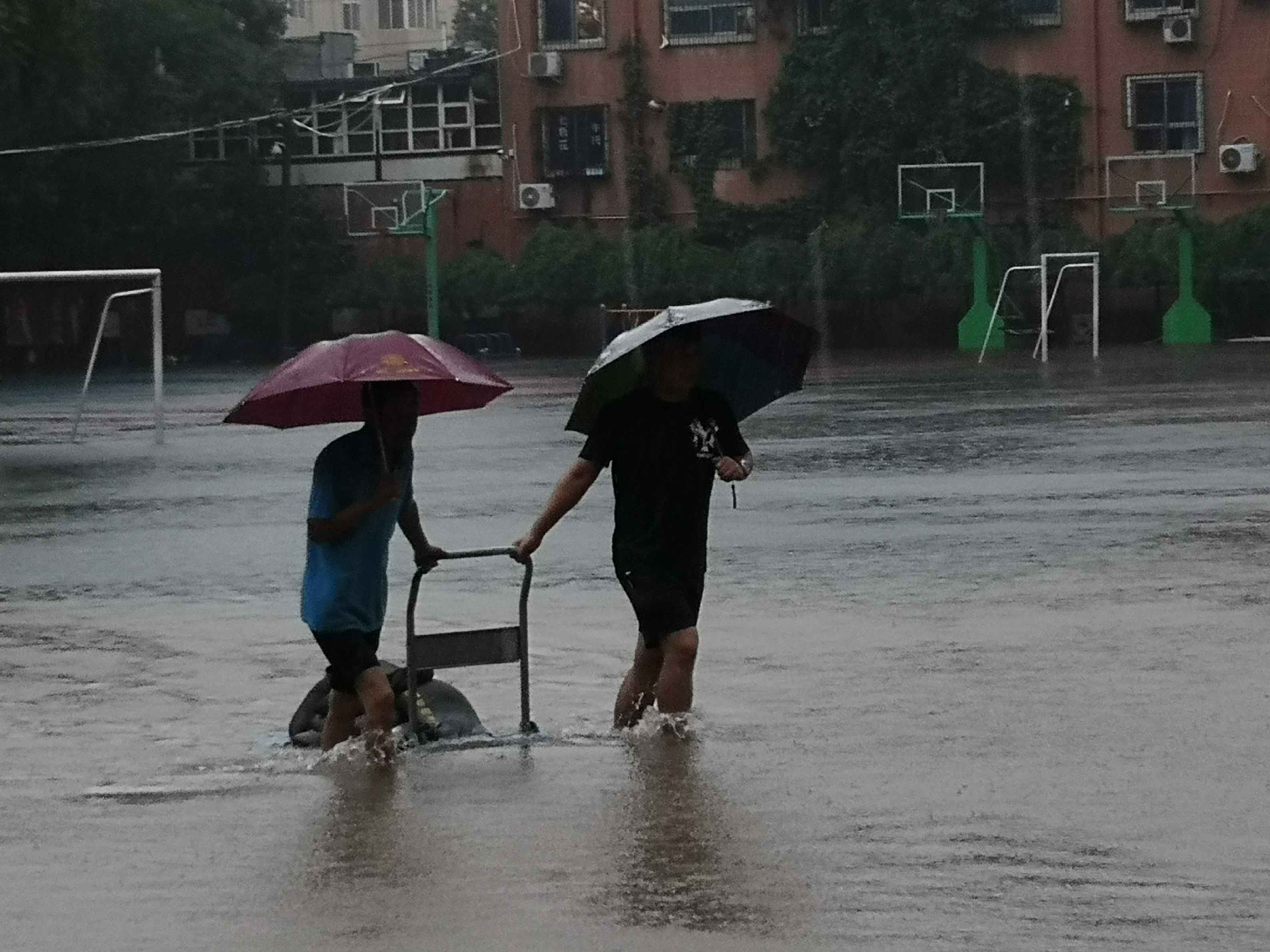 农科路小学冒雨拉防汛沙袋封堵学校大门，防止雨水倒灌入校